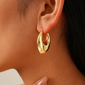 Close-up of polished golden oval hoop earrings with a sleek metallic mirror finish