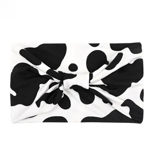 Detail showing high-elasticity fabric headband with black and white cow print and twist knot