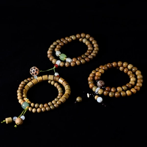Sandalwood beaded bracelets with carved lotus pendants and green jade accents