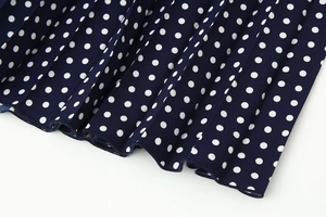 Detail of navy blue and white polka dot pleated fabric with elegant draped texture