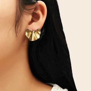 Détail d'un modèle portant une grande boucle d'oreille plissée en éventail plaquée or