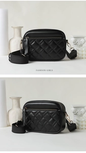 Detail of black quilted crossbody bag with metal zipper and wide strap on white base