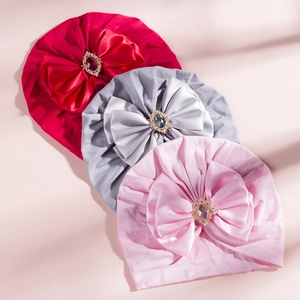 Close-up of baby turban hats with large satin bows and rhinestone centered gems