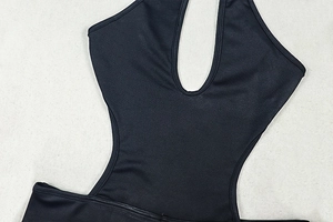 Detail of black cut-out bodysuit with deep U-neck and waist hollow design on grey fabric