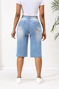 Detail view of the back pockets and washed light blue denim finish of bermuda shorts