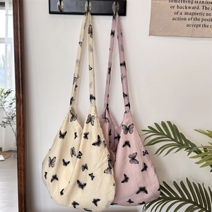 Detailed view of beige and pink lace butterfly tote bags hanging on a minimalist wall