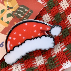 Close-up of a glossy red and white Santa hat hair claw clip with star patterns