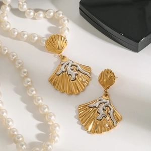 Luxurious gold and silver seashell earrings with coral details and pearls on a display