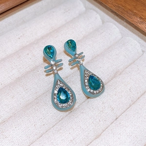 Vue macro de boucles d'oreilles en émail bleu avec cristaux de zircon et pierres de goutte