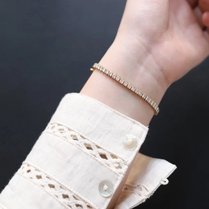 Detailed shot of golden tennis bracelet with rectangular clear zircons on lace cuff