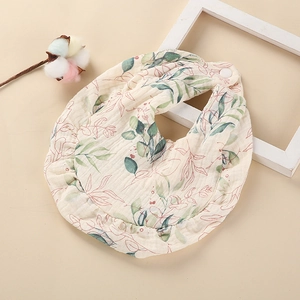 Détail d'un bavoir en gaze de coton pour bébé avec imprimé feuilles et bords volantés