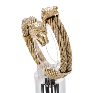 Gold-plated stainless steel cable bracelet with punk style wolf heads on a display stand