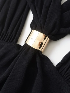 Close-up of black knit fabric texture featuring a shiny gold metal ring buckle detail