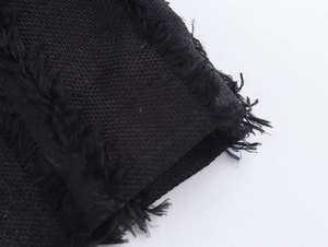 Close-up of black textured woven fabric with frayed edges on long double-breasted coat