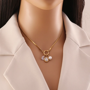 Golden snake chain necklace with zircon pendants and white pearl on a model