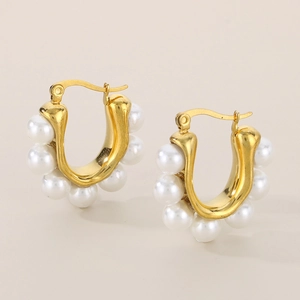 Detail view of 18k gold-plated C-shaped earrings with embedded white pearls and click closure