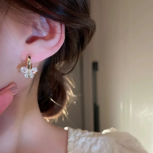 Gold plated butterfly hoop earrings with sparkling cubic zirconia on a female model