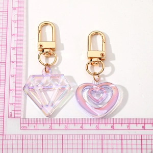Iridescent acrylic heart and diamond keychains with golden metal clasp on scale mat