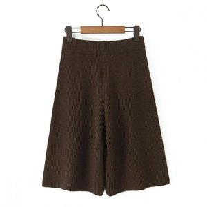Detail of dark brown knitted shorts with ribbed texture hanging on a wooden hook