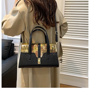 Detail of a color-block handbag with gold scale texture and black pebbled leather base