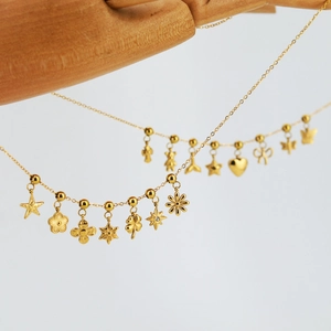 Golden stainless steel necklace featuring star and clover charms on a wooden hand model