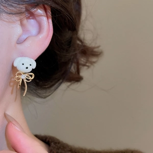 Close-up of 18K gold plated white flocked puppy stud earrings with crystal bow tie detail