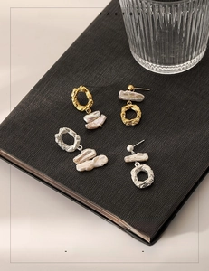 Detailed macro view of asymmetric baroque pearl earrings with textured lava gold metal finish