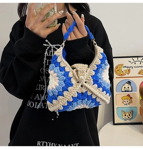 Close-up of handmade crochet shoulder bag with light blue and beige flower patterns