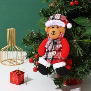 Close-up of a Christmas bear ornament with red plaid fabric hanging on a tree branch