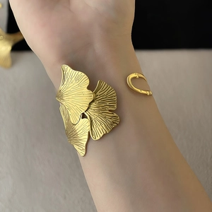 Detailed close-up of golden ginkgo leaf textures and layered metal craftsmanship on cuff