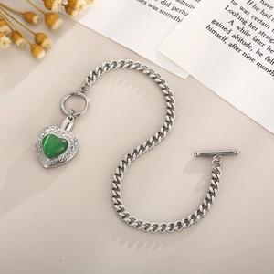 Détail macro du bracelet en acier argenté avec pierre de cœur verte et fermoir en T
