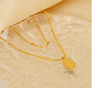 Detailed macro view of gold-plated double-layer necklace with green emerald zircon pendant