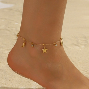 Goldenes Fußkettchen aus Edelstahl mit Seestern- und Muschel-Anhängern am Strand