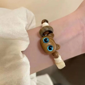 Handmade beaded bracelet with wooden cat head charm and blue eyes on a female wrist