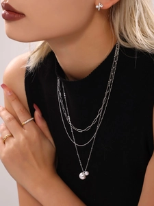 Close-up of a layered silver stainless steel necklace set with pearls worn by a model
