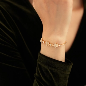Close-up of gold flower bracelet with sparkling zircons on a green velvet background
