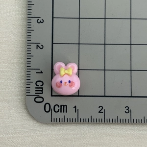 Close-up of a mini pink resin bunny cabochon with bow detail and cm ruler measurement