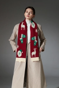 Detail of red Christmas knit scarf with reindeer patterns and ribbed edges on a model