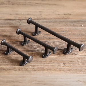 Close-up of three vintage cast iron handles in various sizes on dark wood background