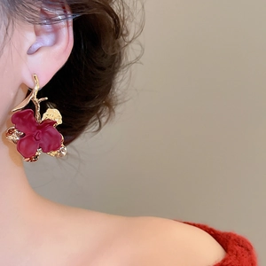 Elegant dark red matte flower earrings with gold trim worn by a model in profile view