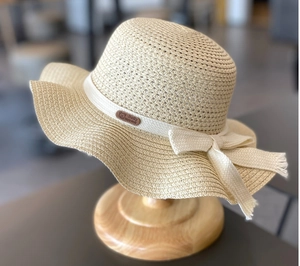 Close-up of summer straw hat for girls with woven ribbon bow and leather baby logo tag