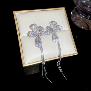 Macro shot of silver flower earrings with sparkling zircon stones and long tassel chains