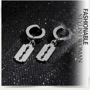 Macro detail of silver stainless steel razor blade earrings on a dark glitter background