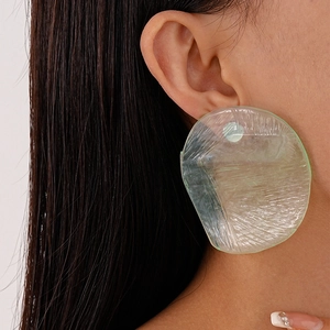 Close-up of translucent light green irregular resin earrings worn by a model