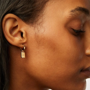 Detailed view of a gold S925 sterling silver hoop earring with star engraved pendant