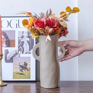 Moderne unregelmäßige matte Keramikvase mit Ringgriffen und bunten Kunstblumen