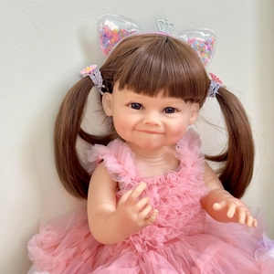 Bambola reborn realistica da 55cm con codini castani e abito tutu rosa in vista frontale