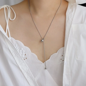 Minimalist silver long Y-shaped adjustable bead necklace on a model wearing a white shirt