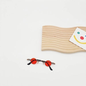 Detailed view of mini round pet sunglasses with red lenses and golden metal frame