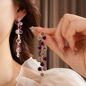 Vue détaillée de longues boucles d'oreilles dorées avec roses violettes et cristaux